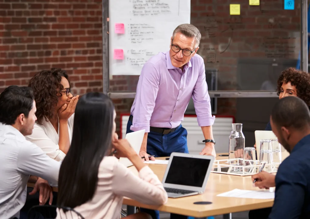 Team in a meeting discussing marketing strategy and lead generation timelines, with a leader presenting at the table.