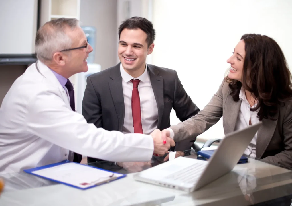 Business professionals shaking hands with a person in a white coat, symbolizing successful lead generation and building trust through inbound marketing.